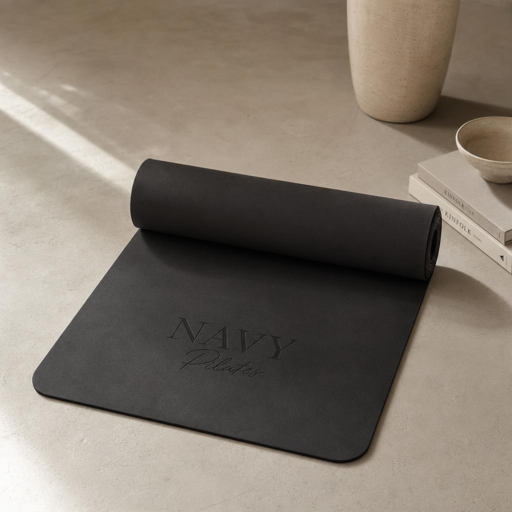 Matte black Navy Pilates mat unrolled in soft morning light